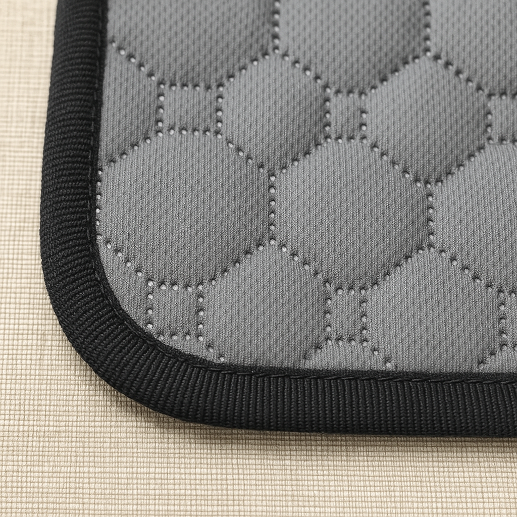 Close-up of a gray quilted mat with black border on a beige surface