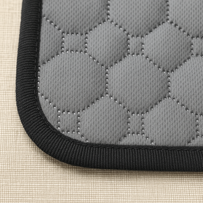 Close-up of a gray quilted mat with black border on a beige surface
